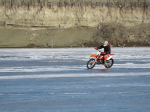 A person on a motorcycle riding across an ice covered lake.