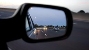 A car 's side view mirror reflecting the road.