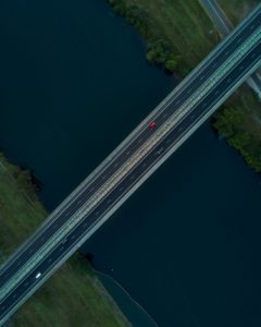 A road with cars driving on it near water.