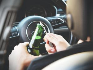 A person drinking beer while driving in the car.
